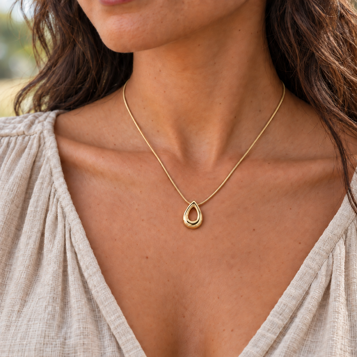 solid 14K yellow gold Teardrop keepsake pendant worn on an adult model