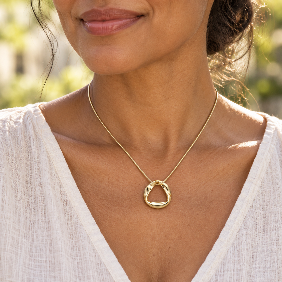 Solid 14K gold Gentle Twist pendant worn on a matching gold snake chain
