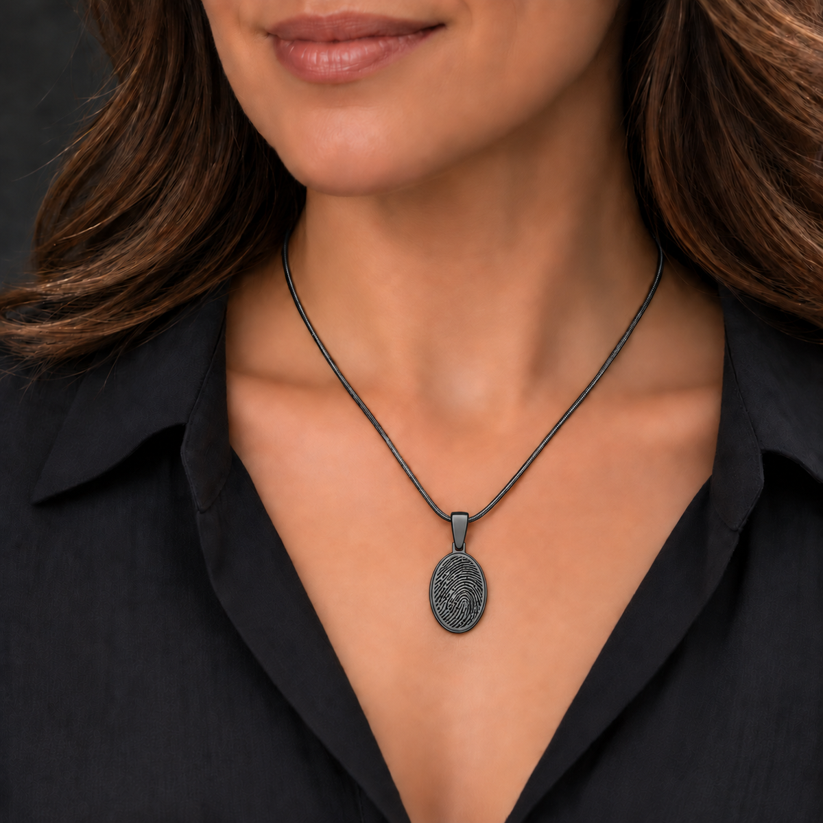 Black-plated oval fingerprint necklace worn on a matching snake chain