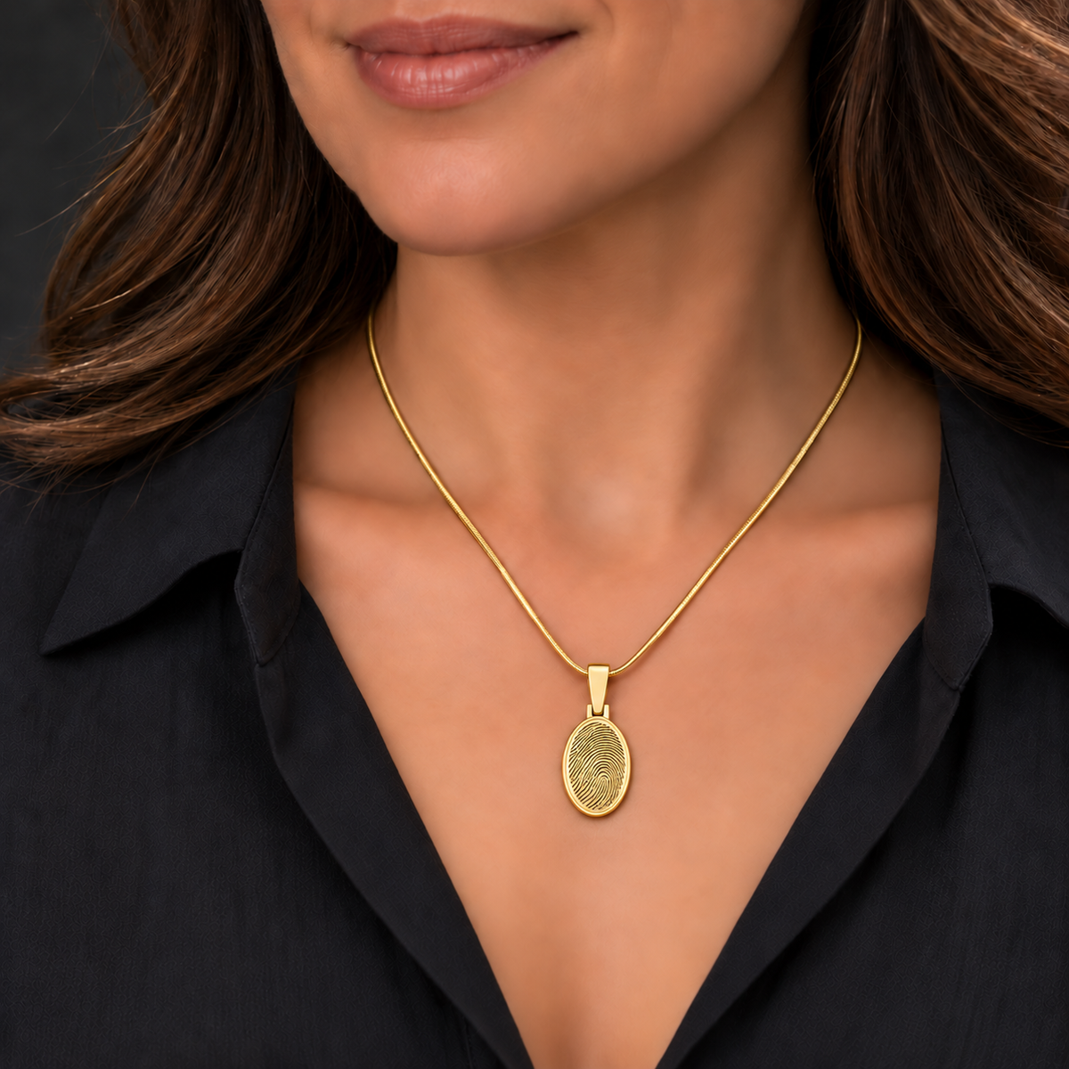 Gold-plated oval fingerprint necklace worn on a matching snake chain